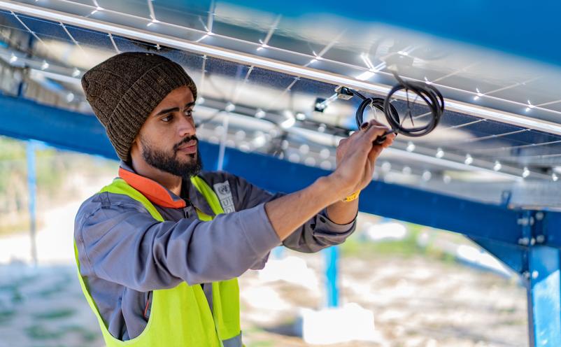 Worker installing solar panels - representing sustainable development